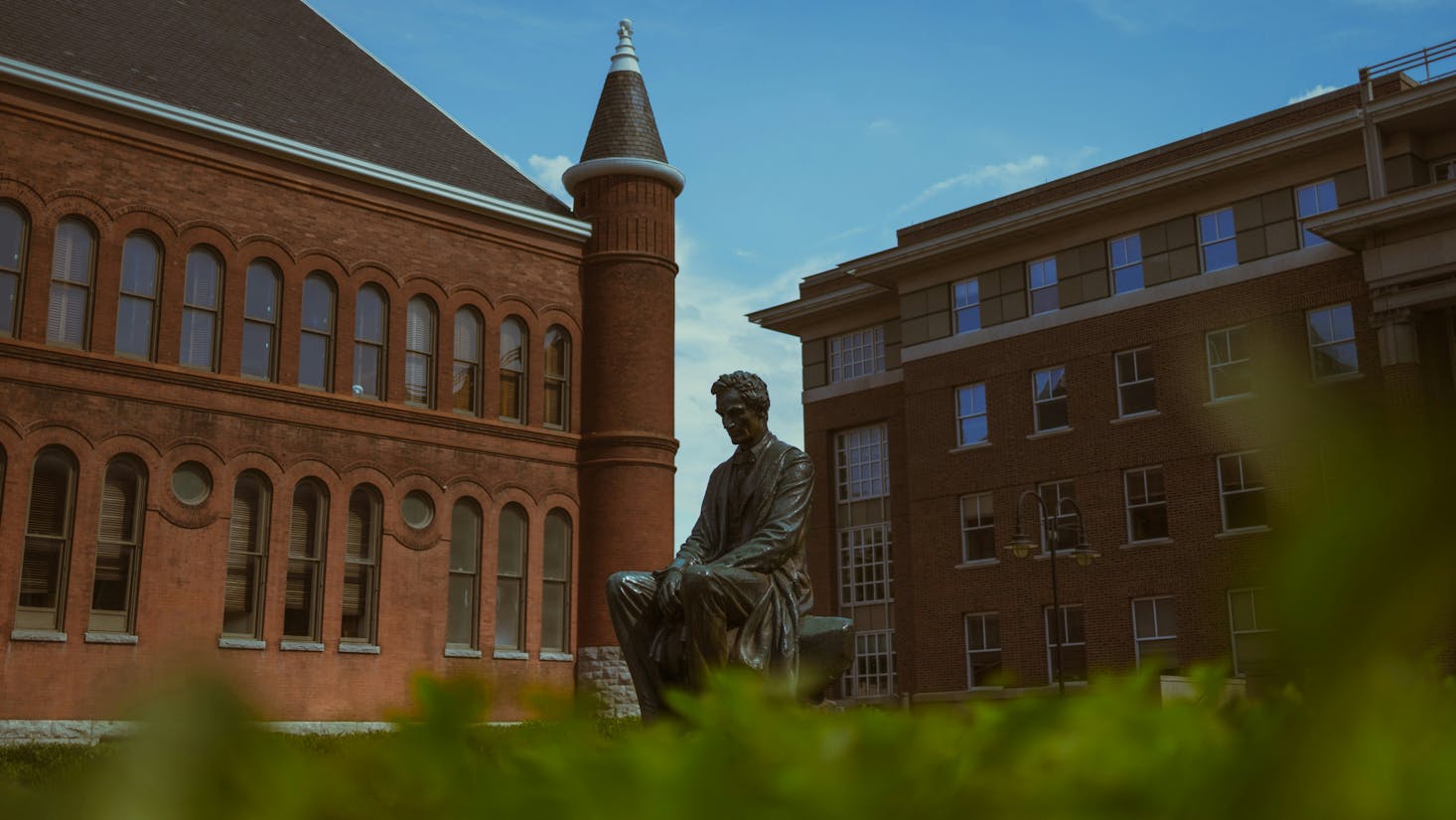 Red brick building with a statue in front of it at Syracuse University in New York