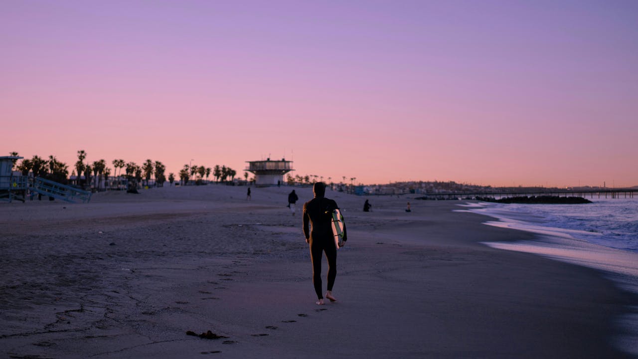 Surfer walking along Venice Beach at sunrise