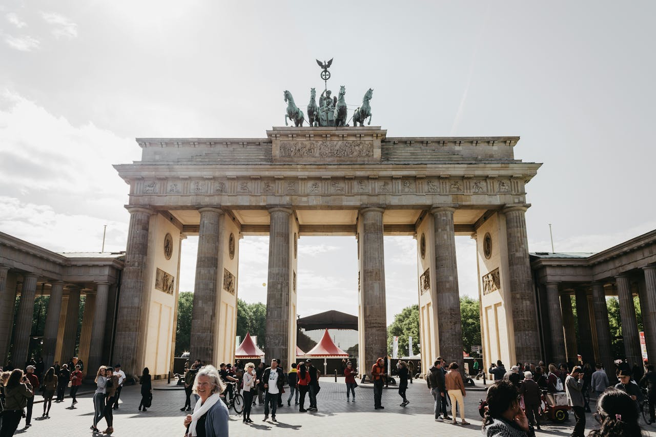 Porta di Brandeburgo, Berlino, con passanti in primo piano e cielo chiaro sullo sfondo