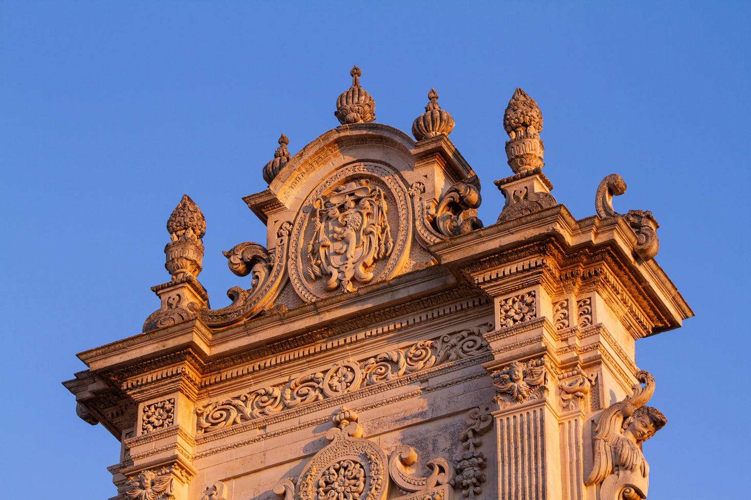 Parte superiore della facciata della Cattedrale Maria Santissima Assunta, il Duomo di Lecce, con cielo azzurro sullo sfondo