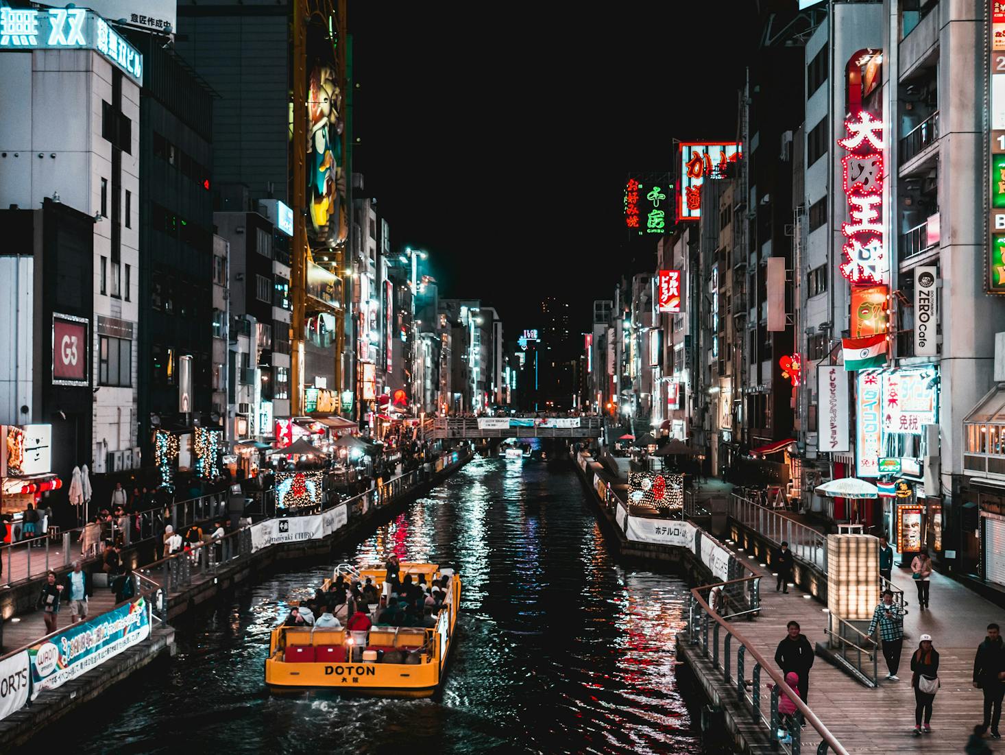 Osaka's Dotonbori District at night with a boat on a canal surrounded by neon signs