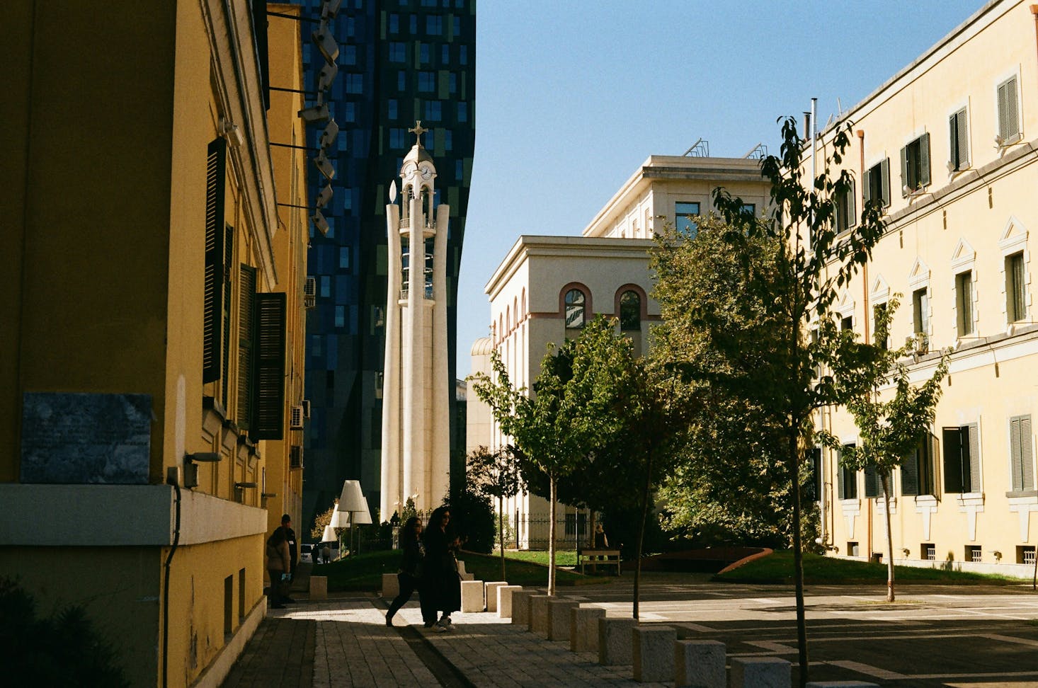 Via del centro con campanile e edifici a Tirana, Albania, con cielo azzurro sullo sfondo