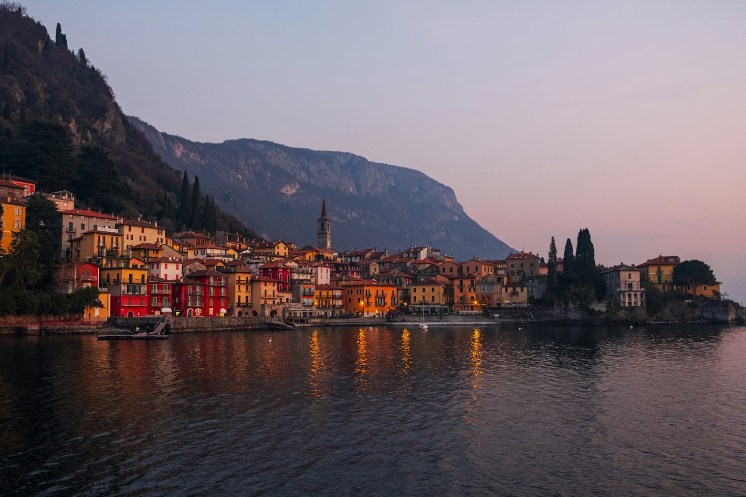 Il Lago di Como con case, edifici e luci sullo sfondo che riflettono sull'acqua 