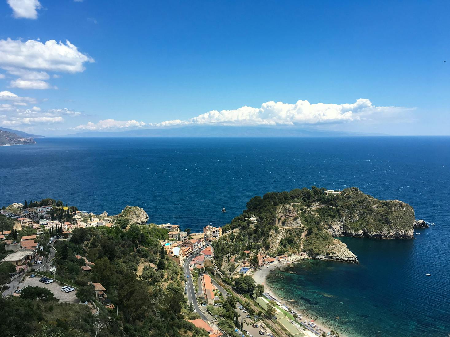 Vista dall'alto sulla costa di Taormina, col mare cristallino e il cielo azzurro sullo sfondo