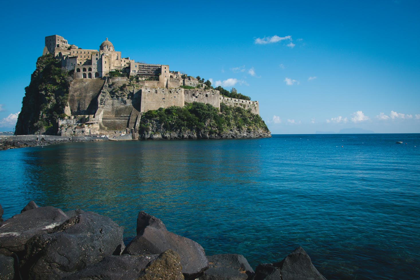 Castello Aragonese a Ischia, Napoli, con mare cristallino in primo piano