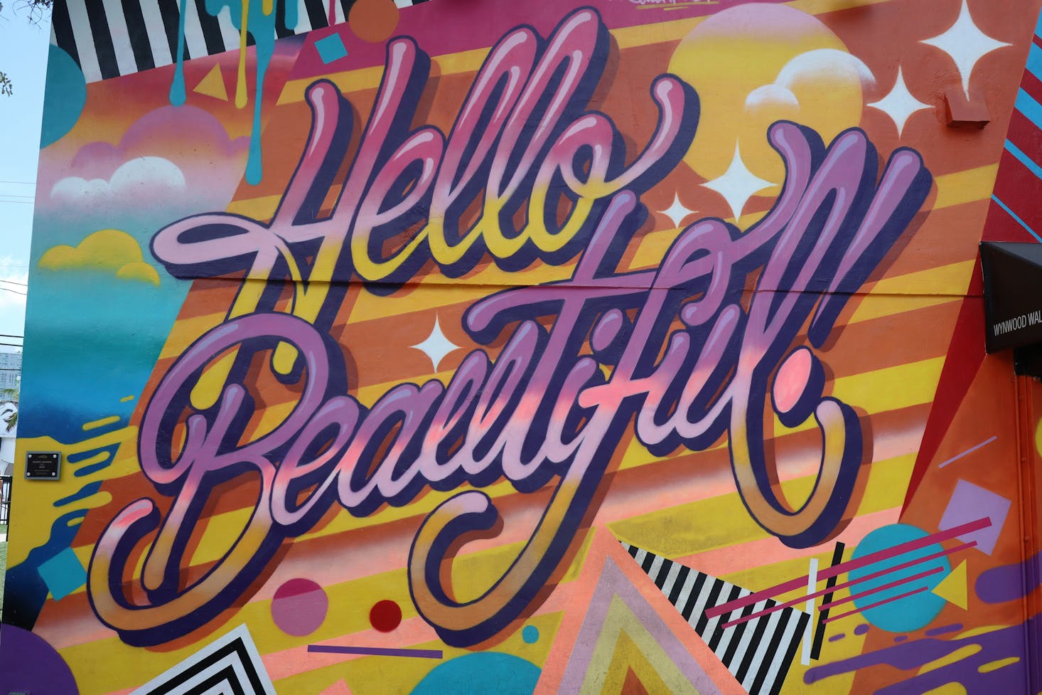 Graffiti with an ombre "Hello Beautiful" in pink, purple, and yellow at Wynwood Walls in Miami