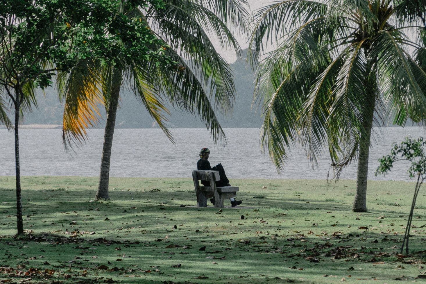 A woman sitting at a bench in green Changi Beach, Singapore