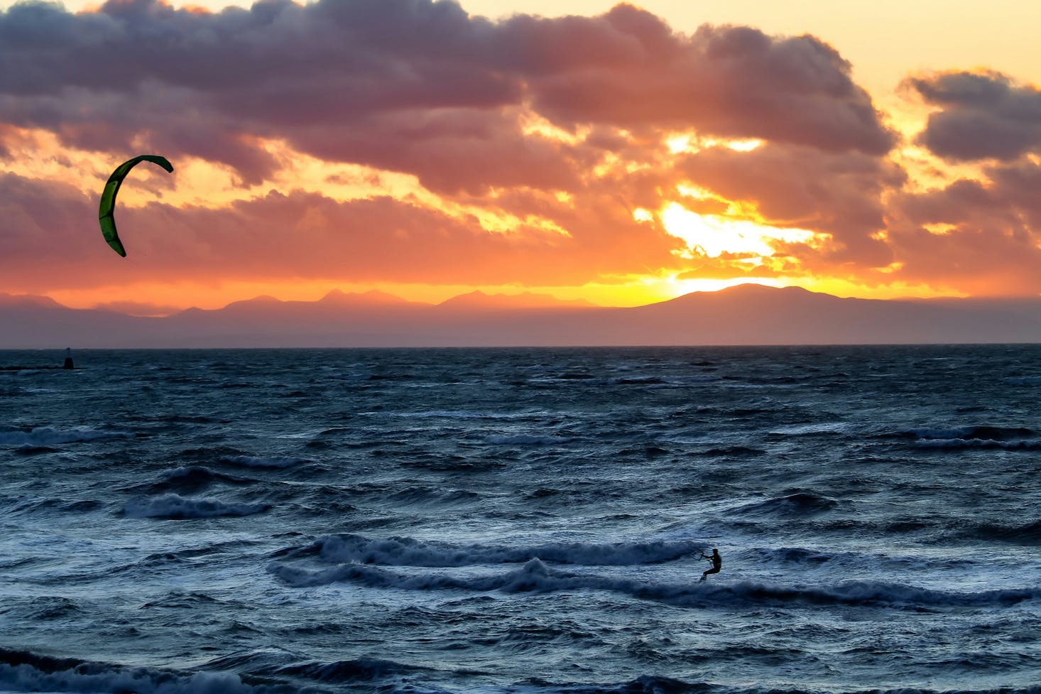 A kite surfer on the water at Wreck Beach at sunrise