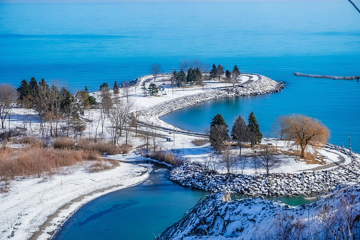 The view of Bluffer's Beach from the Scarborough Bluffs with deep blue water and snow along the shores