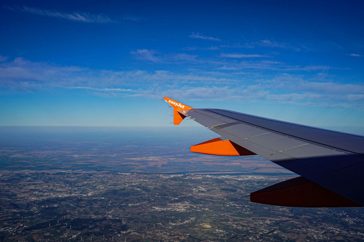 A panoramic aerial view of Lisbon from a plane in flight with the aircraft wing visible