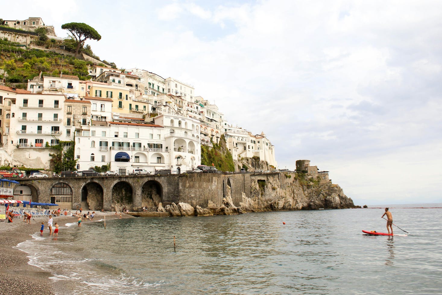 Spiaggia di Amalfi, con edifici a ridosso del mare e persone in spiaggia