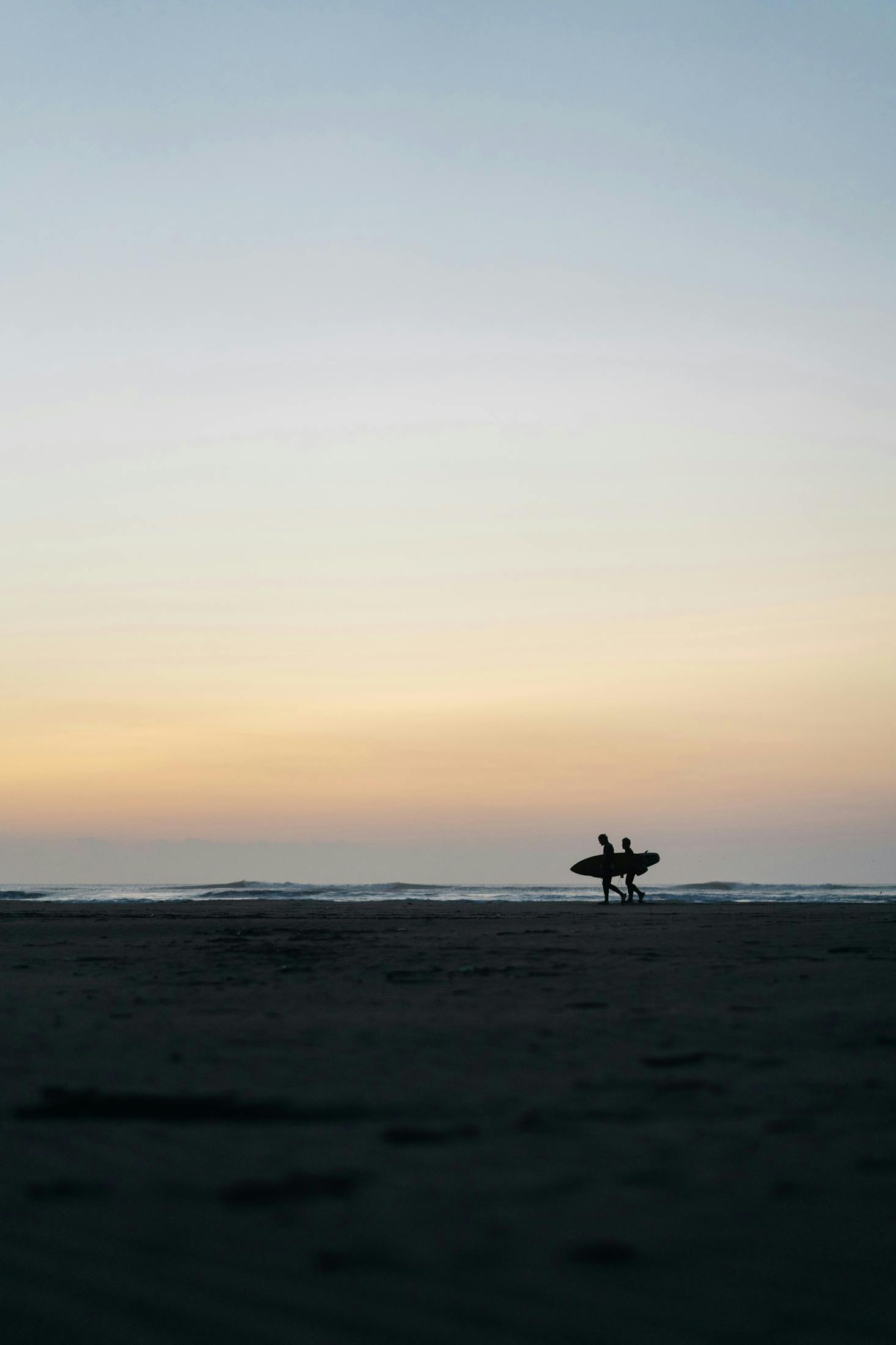 Kujukuri Beach at sunrise with 2 surfers walking in the shadows 