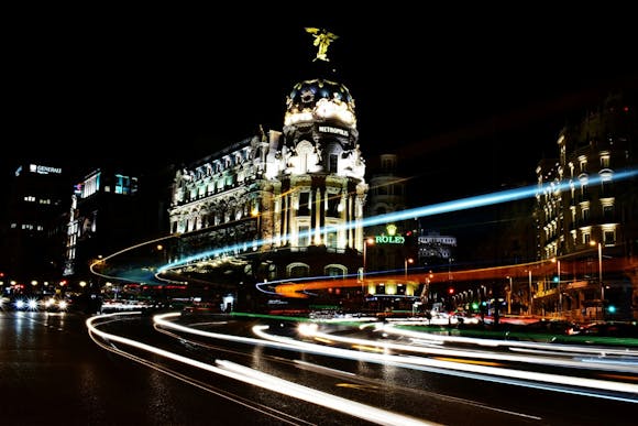 Metropolis building lit up in the night, with car light streaks on the streets 