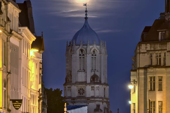 Tom Tower, a bell tower in Oxford, lit up by moonlight and streetlights at night