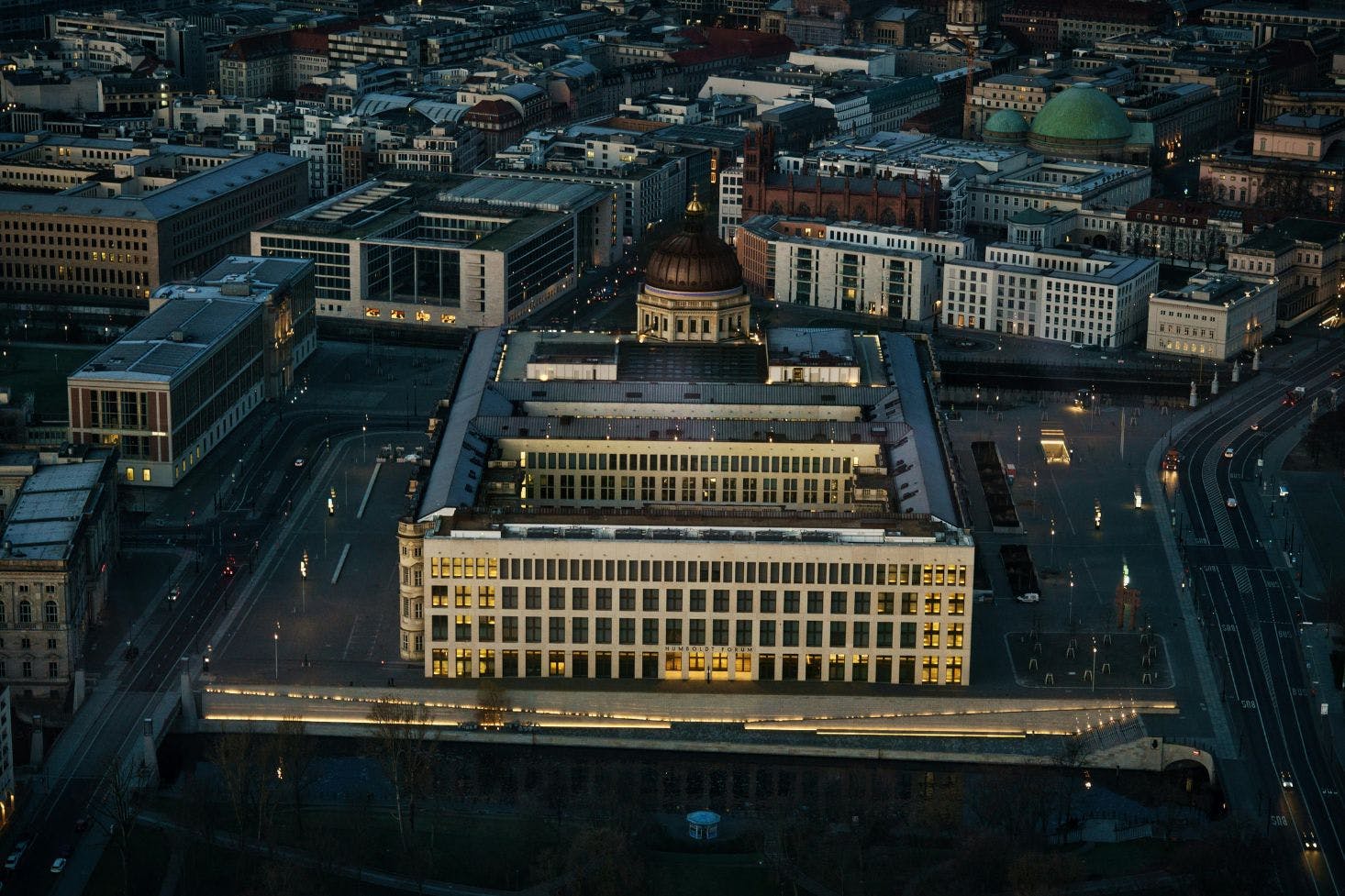 A night cityscape of Berlin with Humboldt Forum Berlin in the center, surrounded by other buildings 