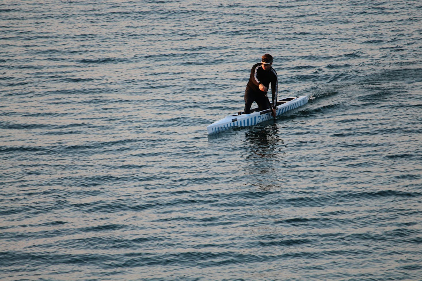 A person in a wetsuit in a blue kayak on Lake Garda