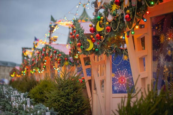 A row of spruce trees in front a building decorated in Christmas decorations