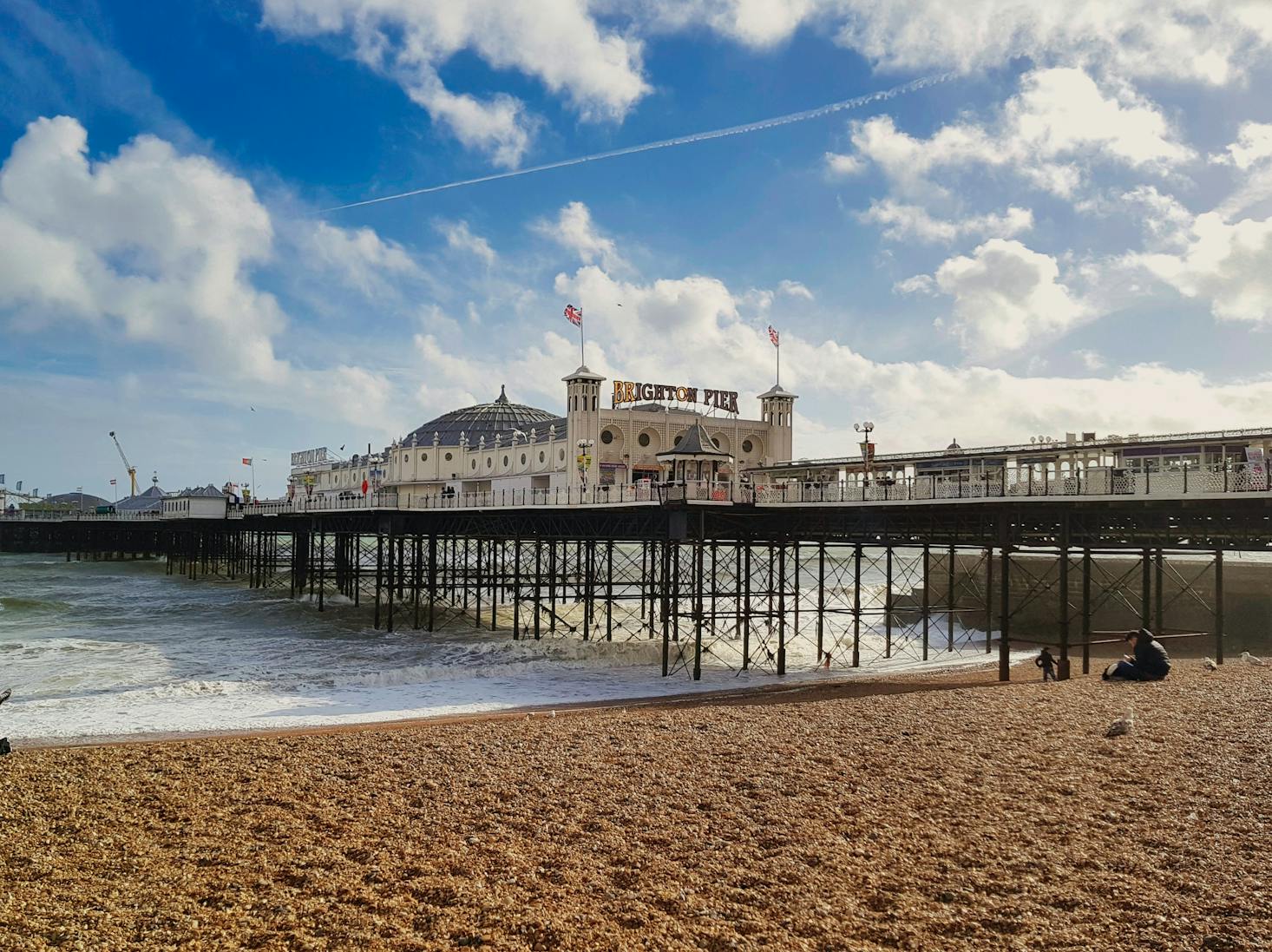 The off-white Victorian-era Brighton Palace Pier building with blue sky and fluffy white clouds