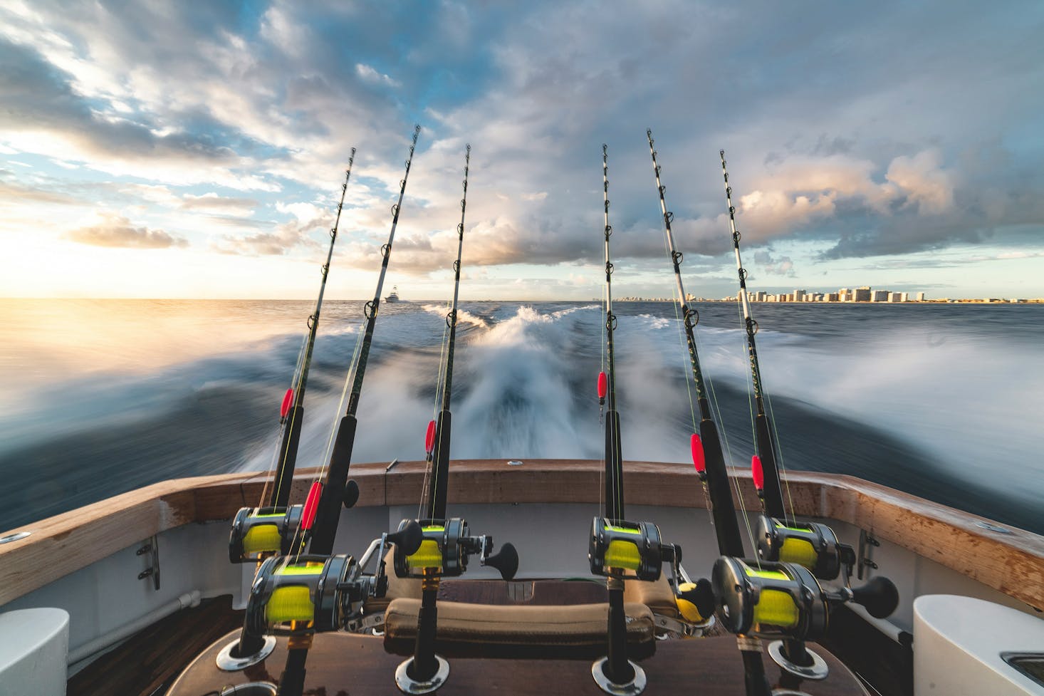 A boat with 4 fishing rods traveling fast away from Fort Lauderdale Beach