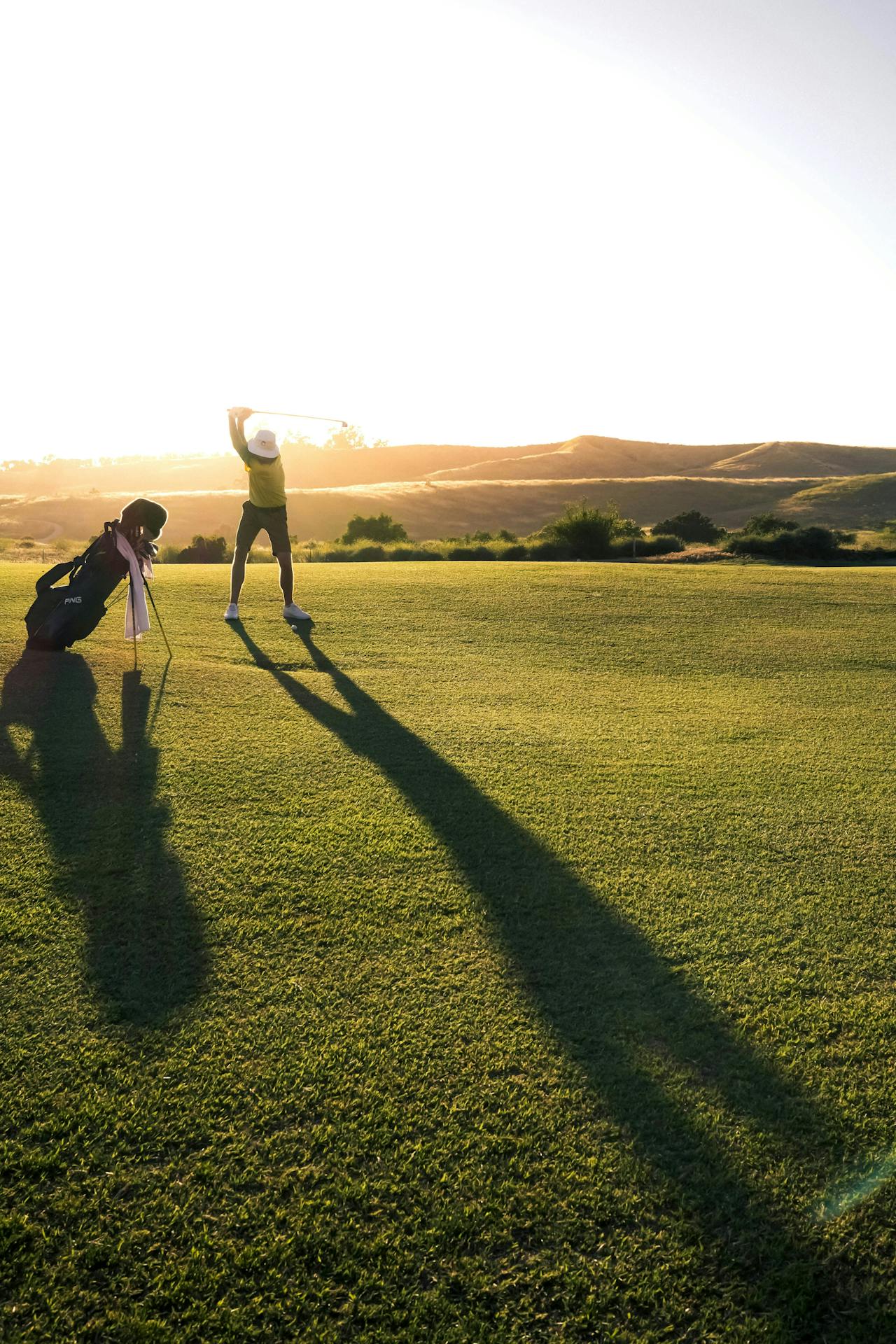 Golfer standing beside his equipment on a lush green golf course at Rustic Canyon, with the sun casting a beautiful shadow