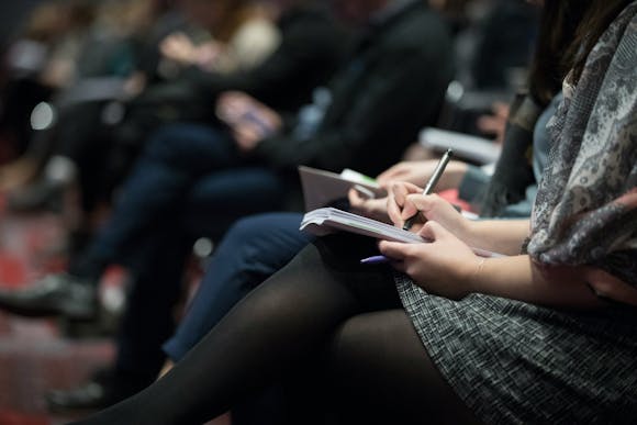 Conference participants writing in notebooks while seated, reflecting the informative sessions at KBIS