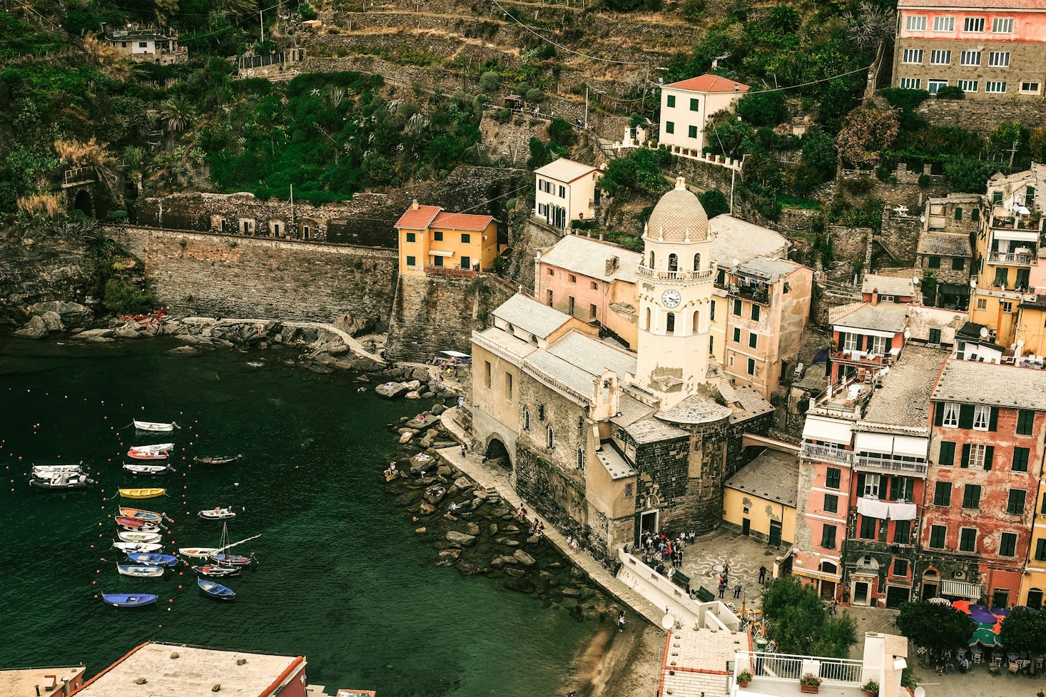 Vista su Vernazza dall'alto, con mare cristallino sulla sinistra e edifici tipici arroccati sulla destra