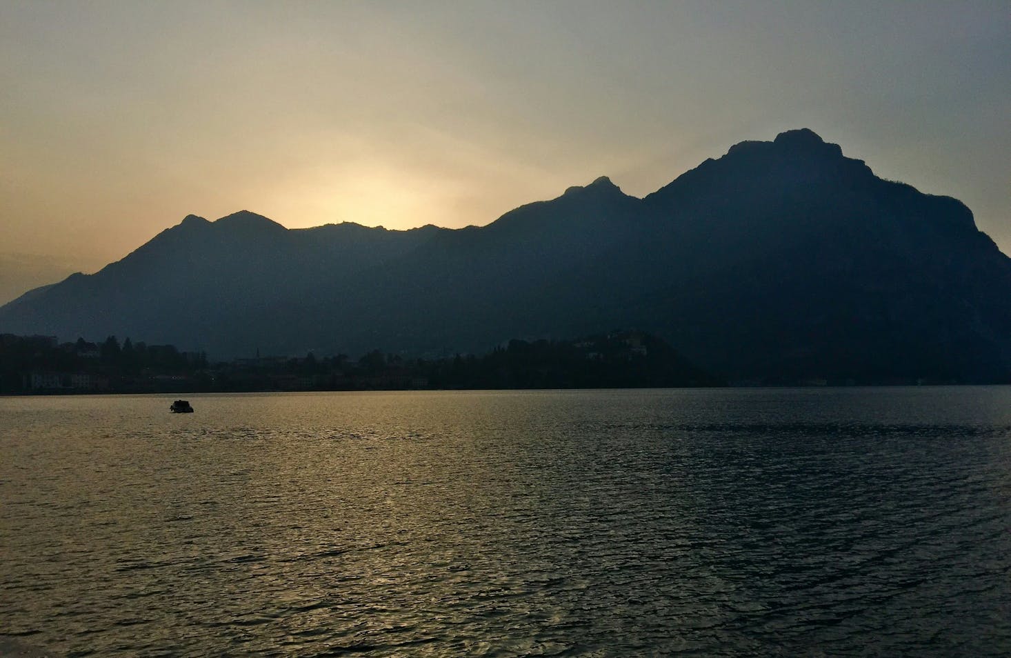 Lago di Como a Lecco, con monti sullo sfondo e sole al tramonto