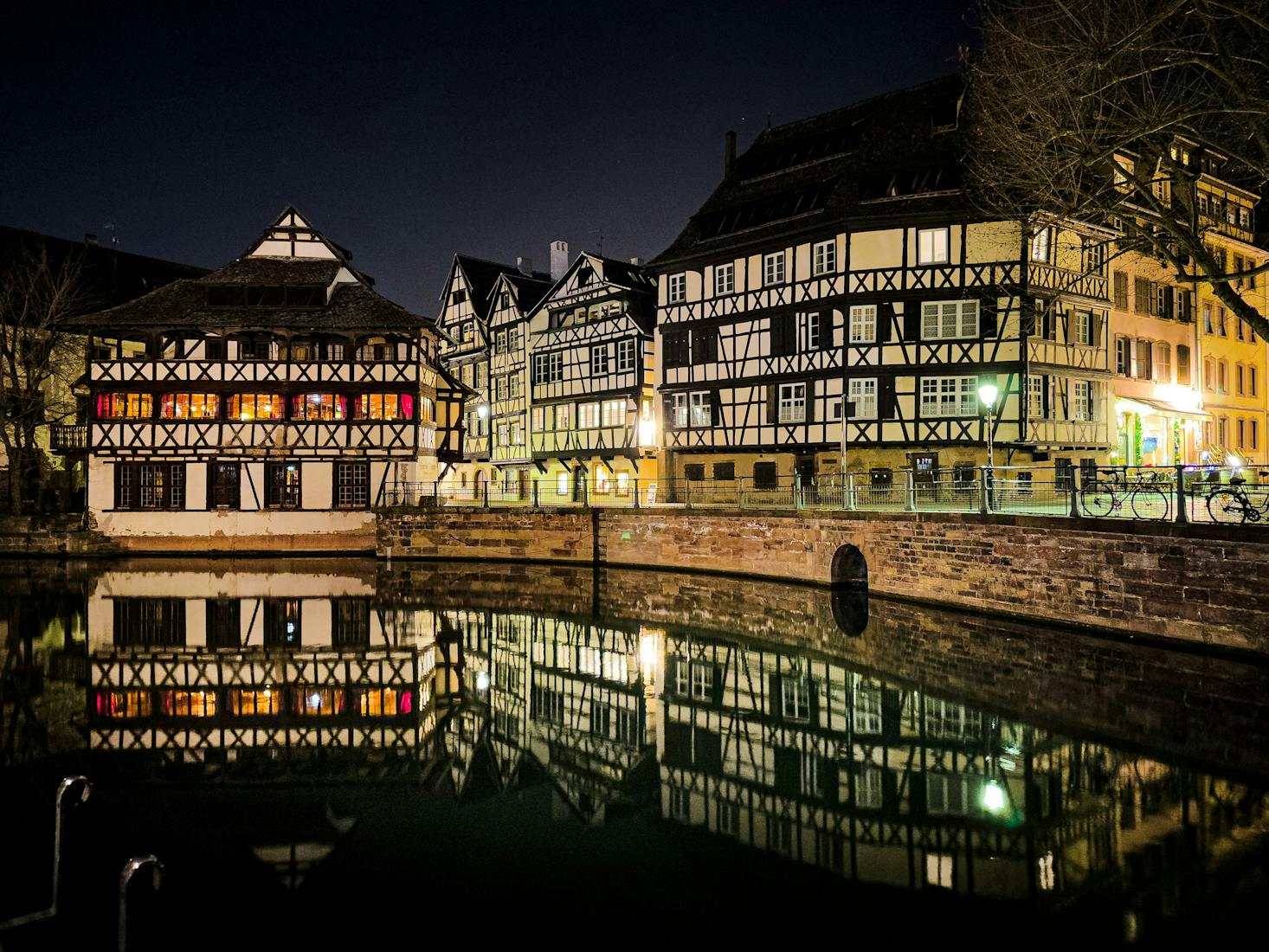 Half-timbered houses along a canal lit up at night in Strasbourg