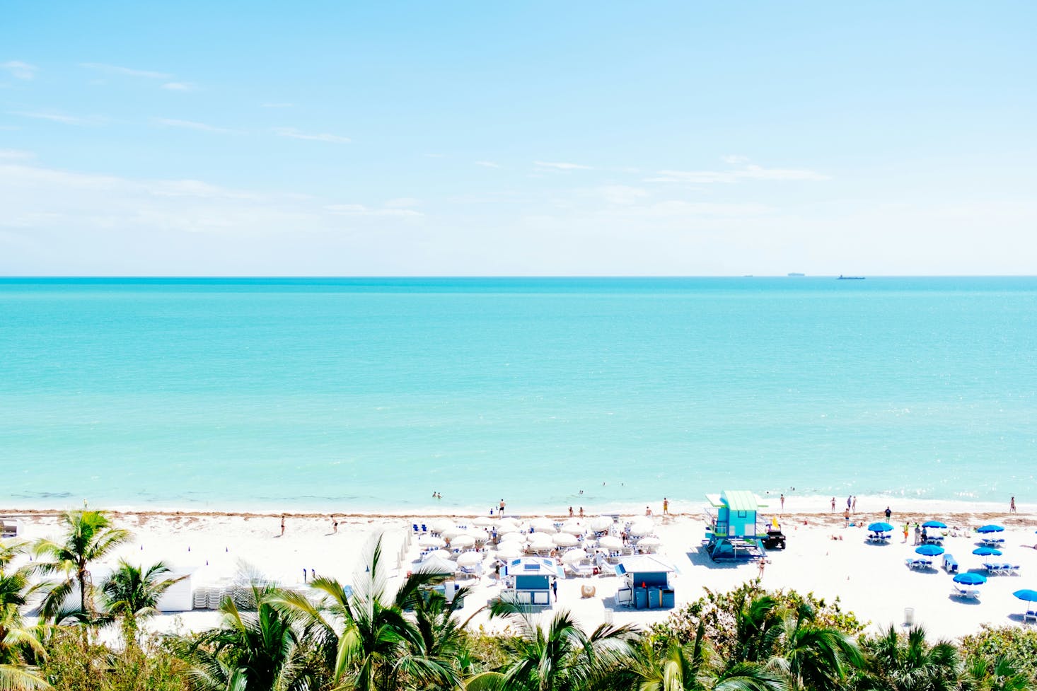 Clear turquoise water and a beach club on the white sands of Miami Beach