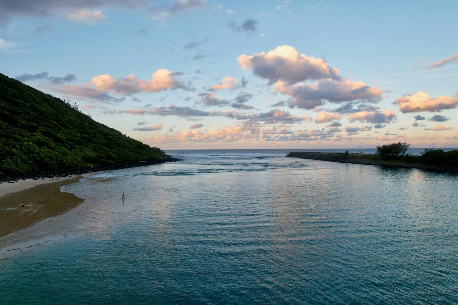 Calm water flanked by a dark hill at Tallebudgera Creek Beach near Gold Coast 