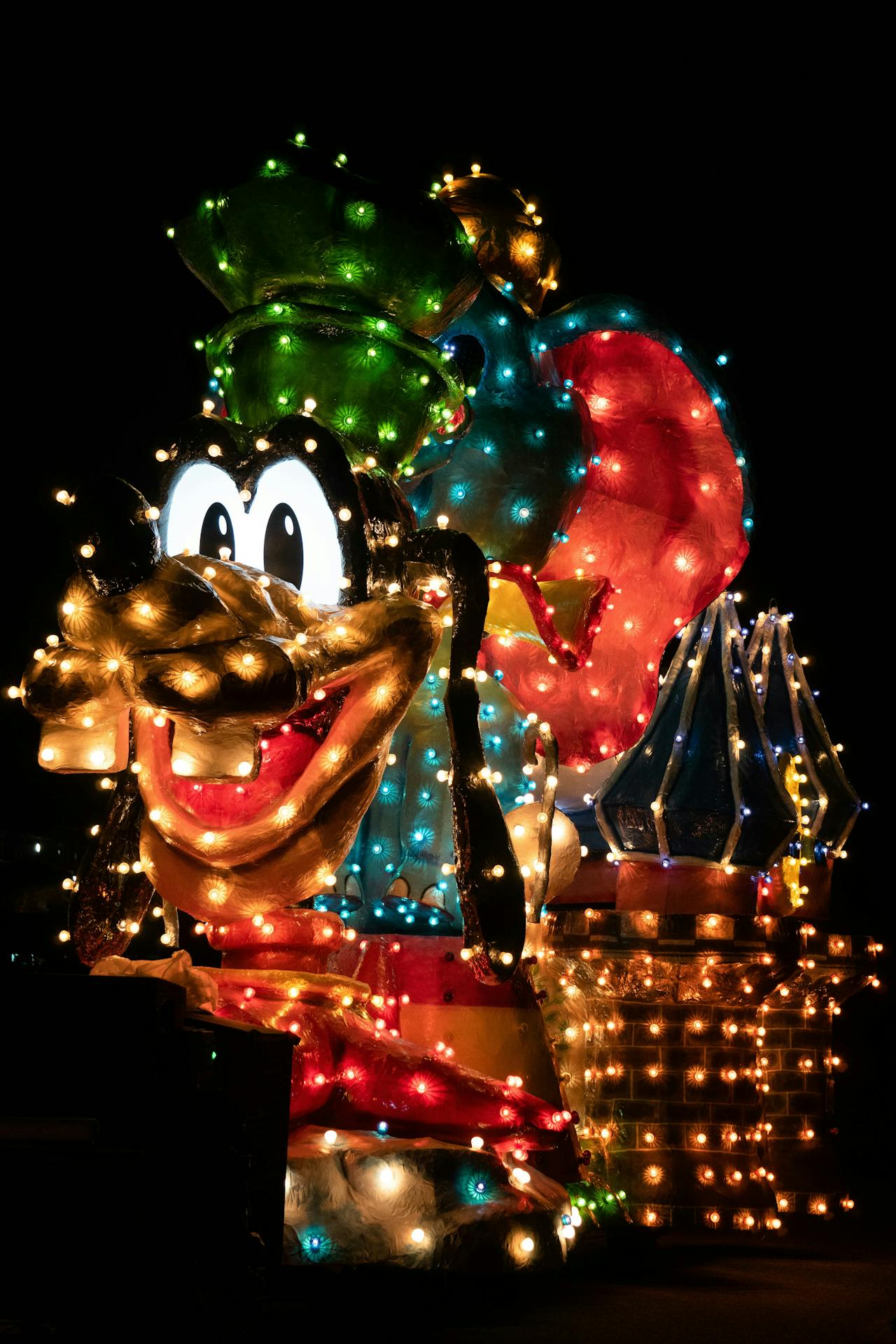 Brightly lit parade float of the cartoon character Goofy from Disney at night