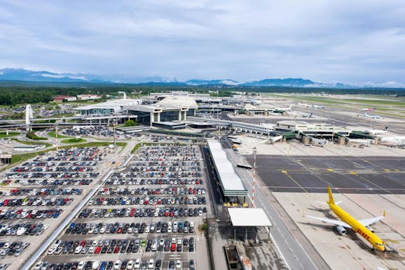 A view of Milano Malpensa Airport, a crowded parking lot, and a DHL plane on the tarmac