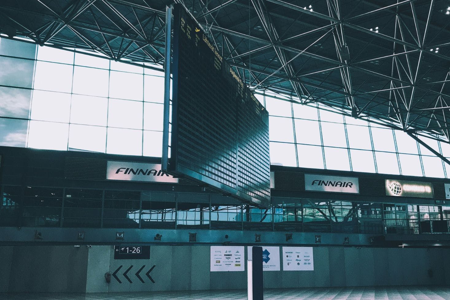 Inside Helsinki-Vantaa Airport with boarding info displays, gate signs, and Finnair branding visible on the windows