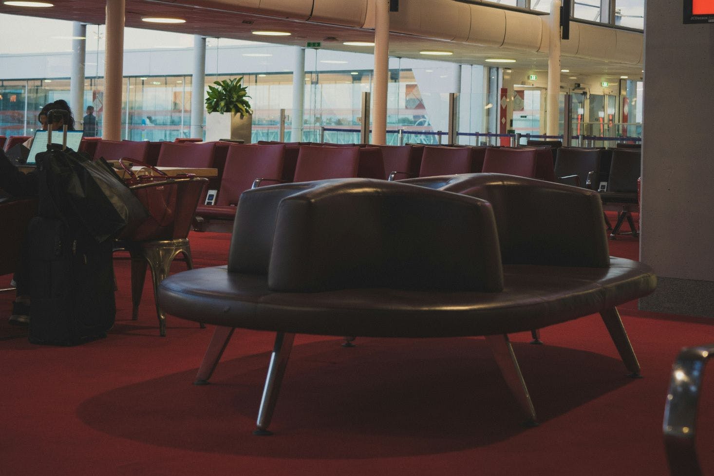 Burgundy leather seating at Charles de Gaulle Airport in Paris with a window view in the background