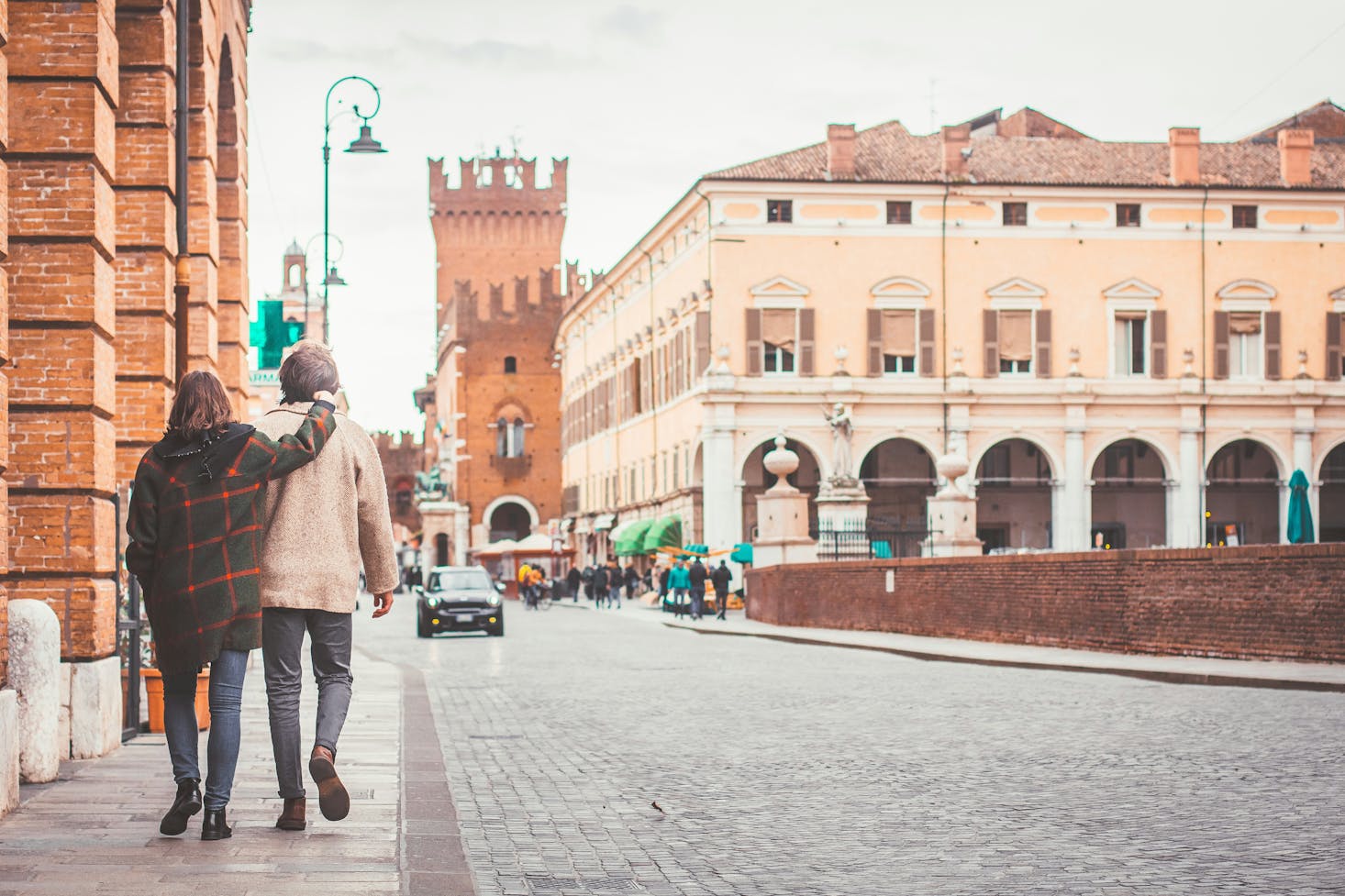 Persone che camminano in piazza a Ferrara, con edifici storici sullo sfondo