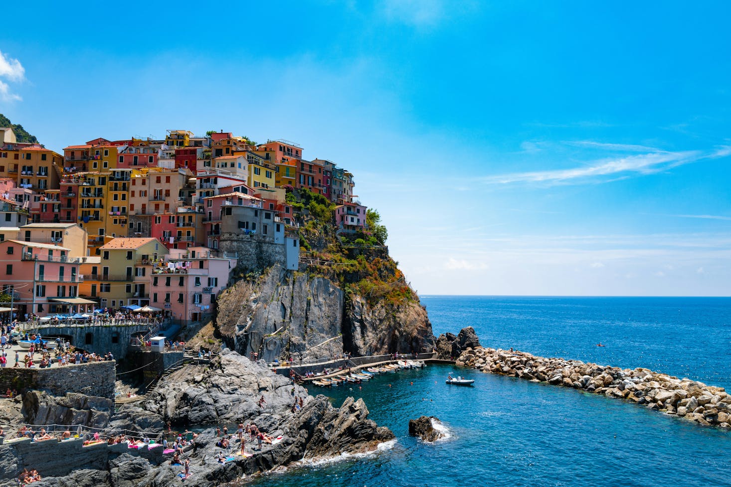 Casette colorate ed arroccate di Riomaggiore con mare azzurro sulla destra