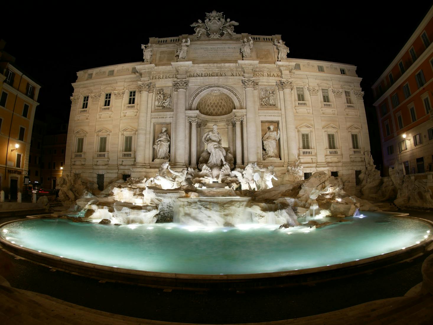 The water of the ornate Trevi fountain lit up at night in Rome