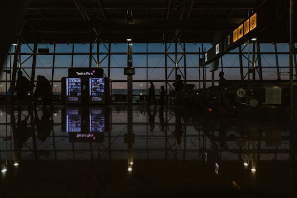 A night view of the 'Fly and Tech' vending machine at Brussels Airport, with 'Gates A, B' signs above the escalator