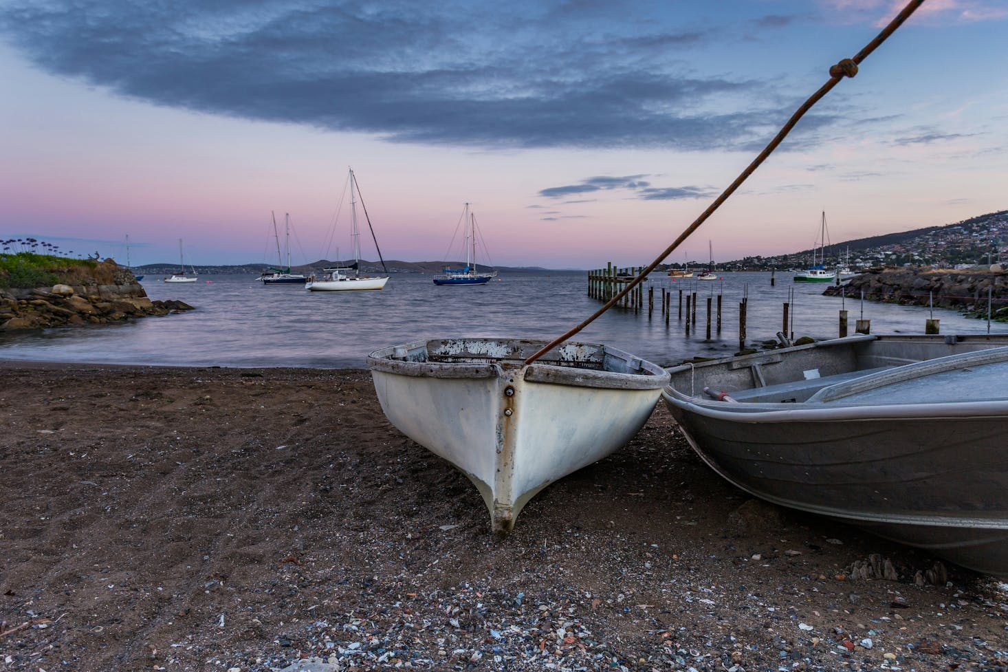 Boats on a rocky beach in Hobart at dusk