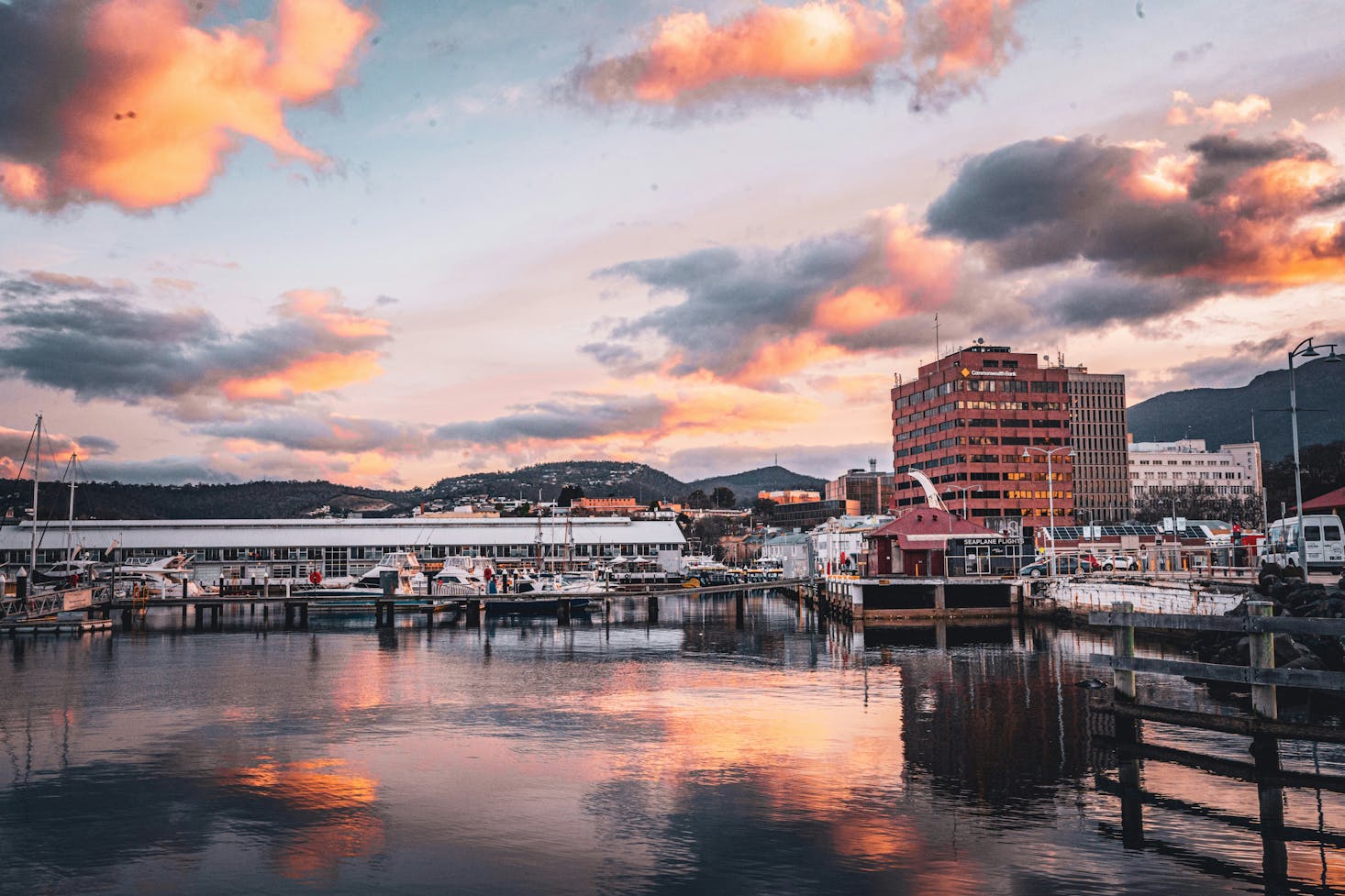 The Hobart waterfront at sunset with orange clouds, a marina, and reflections in the water