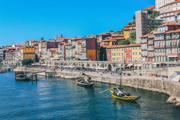 View of Porto with boats on the Douro River, and hillside buildings in the background