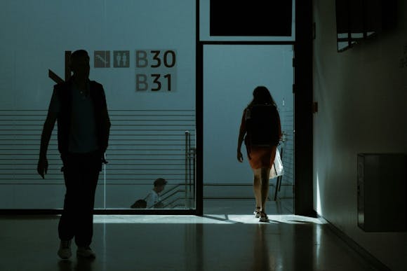 A woman and a man walking toward the staircase through the dark hallway of the Berlin Brandenburg Airport 