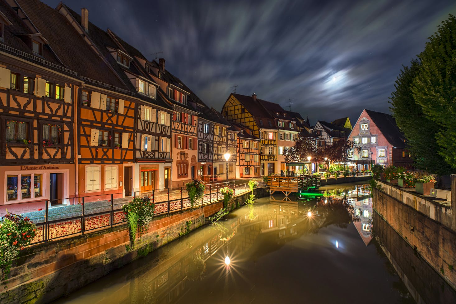 Colorful half-timbered buildings along a canal in Colmar at night