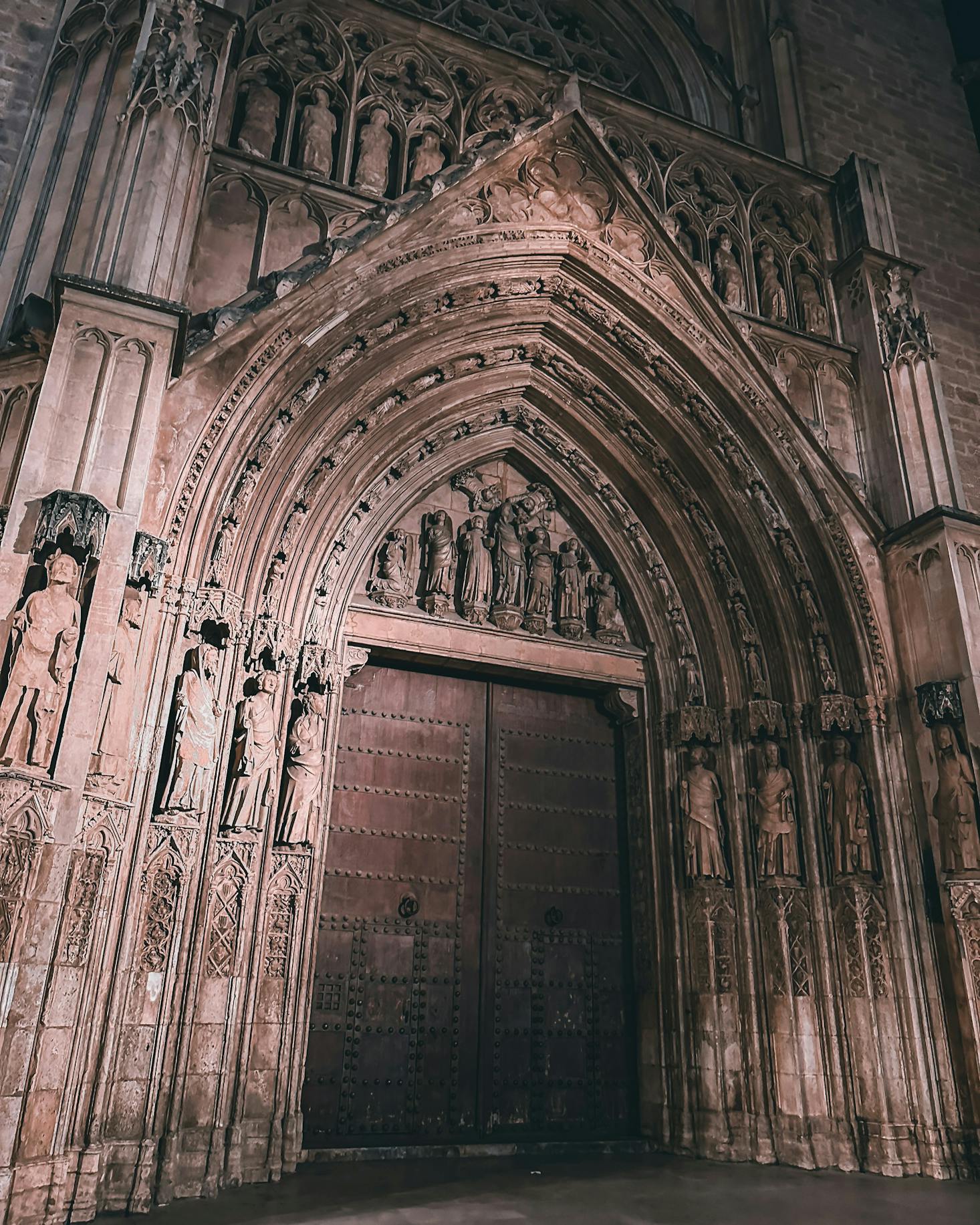 The ornate brown doors of a church in Valencia at night