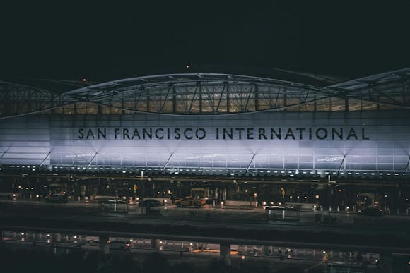 San Francisco International Airport lit up at night, with vehicles parked in front and in the underground parking area