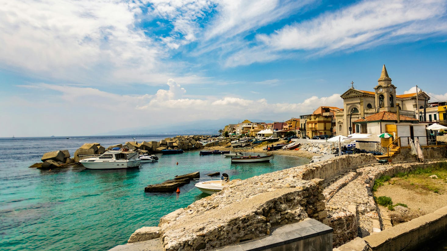 Spiaggia a Messina con acqua cristallina a sinistra e edifici del centro a destra