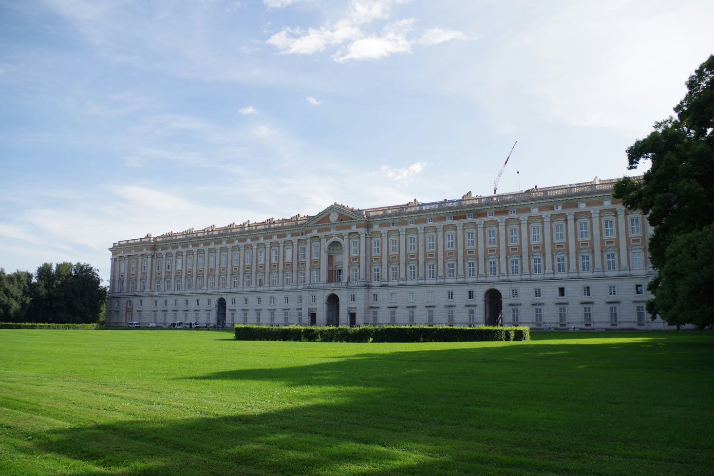 La maestosa Reggia a Caserta, con giardino verde in primo piano e cielo sereno sullo sfondo