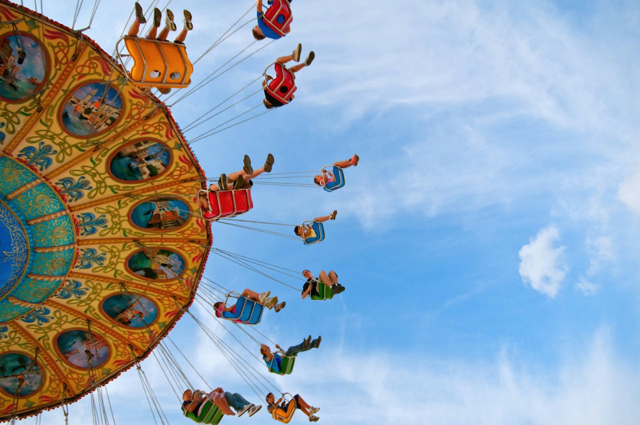 Adults and children riding a carnival ride under a beautiful blue sky