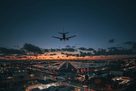 A plane lands at night at San Diego International Airport (SAN), with the city's glowing lights