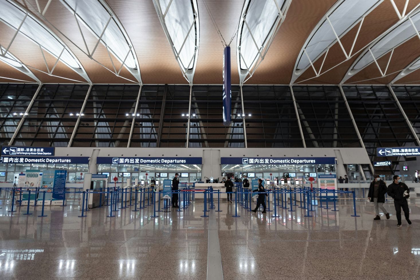 A domestic departures area at Shanghai Pudong International Airport, with high ceilings and a few passengers waiting